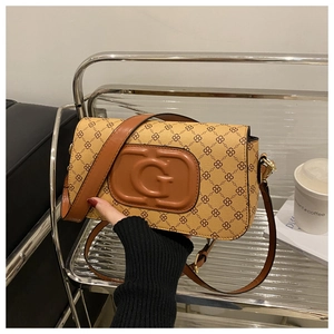 Detail of tan monogram crossbody bag featuring embossed G letter and leather strap