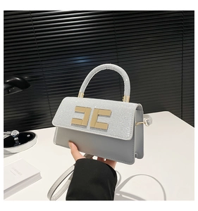Detail of grey crossbody bag with shimmering silver rhinestones and gold clasp