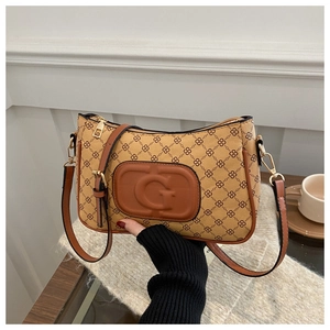 Close-up of brown monogram crossbody bag with golden hardware and G logo detail