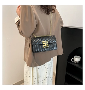 Détail du sac bandoulière vintage noir avec texture plissée et chaîne dorée sur mannequin