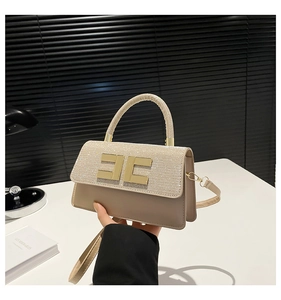 Detailed view of champagne glitter handbag featuring gold metal clasp and leather handle