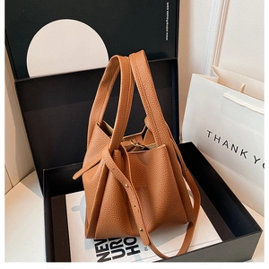 Detail of a brown lychee pattern leather bucket bag with folded design in a gift box