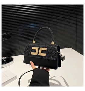 Close-up of black sequin and matte leather handbag with gold metal logo and handle detail