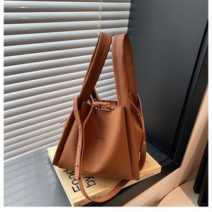 Detail of brown lychee texture bucket bag with Fashion lettering and golden rivets