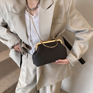 Vintage black shell evening bag with gold chain strap shown on model in street style