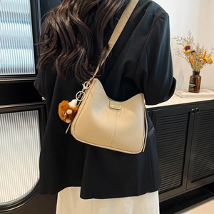 Sac seau hobo beige avec boucle en métal et pendentif ours en peluche sur un mannequin
