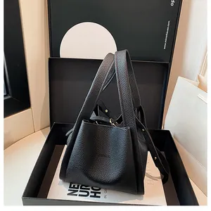 Detail of black lychee grain leather bucket bag with gold hardware in luxury gift box