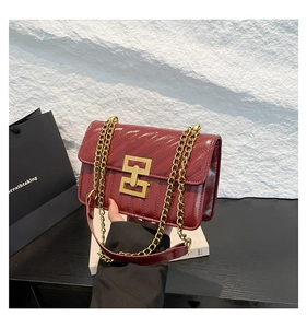Détail du sac rouge matelassé en similicuir avec coutures en V et fermoir doré chic