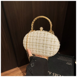 Dettaglio della borsa da sera in tweed con manico circolare dorato e chiusura a gioiello