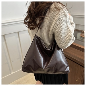 Detail of dark brown glossy patent leather tote bag on model for casual retro style