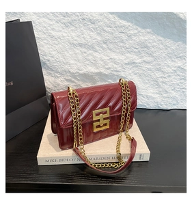 Détail du sac en cuir matelassé bordeaux avec boucle dorée et bandoulière en chaîne