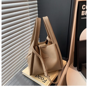 Detail of beige lychee grain bucket bag with embossed Fashion logo and adjustable strap