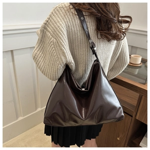 Detail of adjustable wide shoulder strap on a large dark brown oil wax leather hobo bag
