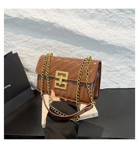 Détail d'un sac bandoulière en cuir verni marron avec matelassage et boucle dorée