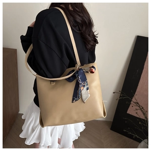 Détail d'un sac cabas beige avec un foulard floral sur la poignée élégante