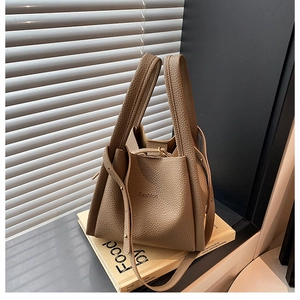 Detail of coffee brown bucket bag with lychee texture and gold-toned Fashion logo