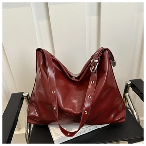 Close-up of wine red oil wax leather hobo bag with metallic grommet adjustable strap