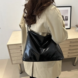 Glossy black hobo bag with adjustable buckle shown on shoulder for daily commute style