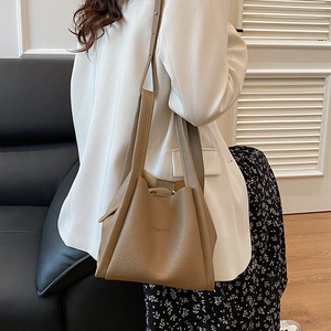 Brown litchi grain leather bucket bag with top handles shown on a model