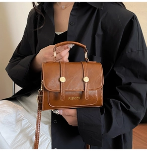 Detailed shot of brown textured leather small square bag with golden fashion metal buckle