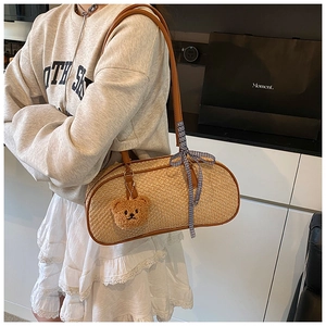 Detail of light khaki woven underarm bag with plush bear charm and checkered bow