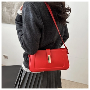 Detail of red leather underarm bag with gold metal buckle shown on shoulder