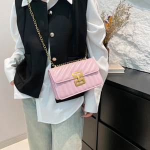 Sac bandoulière en cuir verni rose avec chaîne dorée et boucle géométrique sur mur blanc