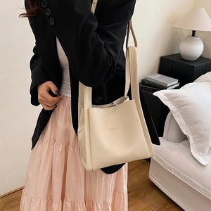 Fashion cream bucket bag with lychee texture and wide strap on model in indoor setting