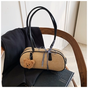 Detail of woven cylinder handbag with black leather straps and blue checkered ribbon bow