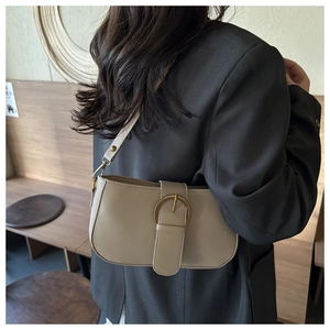 Gros plan d'un sac sous les aisselles en cuir beige avec boucle dorée sur un modèle