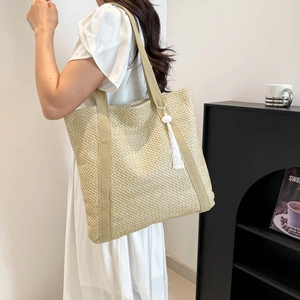 Large beige woven straw tote bag with tassel charm, perfect for beach or summer fashion