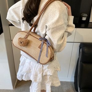 Straw shoulder bag with brown leather strap and cute bear charm for spring fashion
