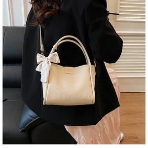 Nahaufnahme der beigen Beuteltasche mit Lychee-Muster, Schleife und Fashion-Prägung