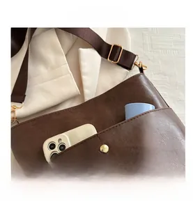 Detail of dark brown retro shoulder bag showing texture, strap and large storage pocket