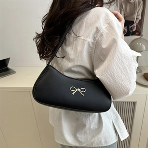 Minimalist black retro underarm bag with gold bow decoration on white shirt model