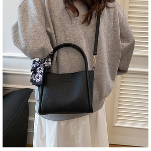 Detail einer schwarzen Beuteltasche aus Leder mit Fashion-Prägung und Karo-Schleife