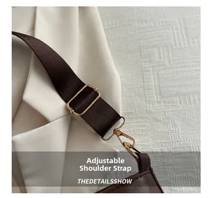 Detail of adjustable fabric shoulder strap with gold metal buckle on dark brown bag