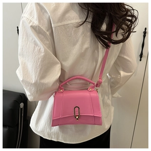 Rosafarbene Lederhandtasche mit goldener Ringschnalle und Schultergurt am Model