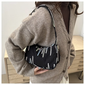 Detailed view of black underarm bag with colorful linear embroidery and textured fabric