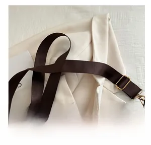 Detail of adjustable dark brown nylon strap with gold metal lobster clasp on leather bag
