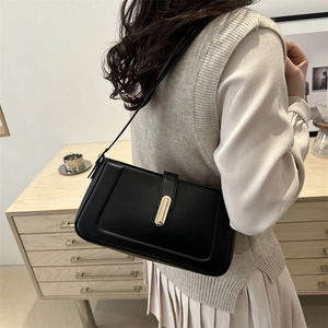 Sac bandoulière minimaliste en cuir noir avec un fermoir rectangulaire en métal doré