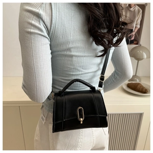 Detailansicht einer schwarzen Lederhandtasche mit Goldverschluss als Umhängetasche
