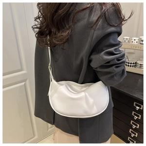 Detail der weißen glänzenden Hobo-Tasche mit Faltenstruktur und Schultergurt