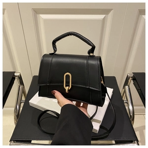 Detail der schwarzen matten Ledertasche mit goldener Schnalle und Griff in Lifestyle-Umgebung