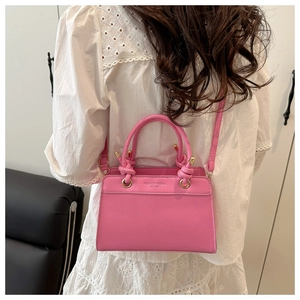 Detail of pink faux leather handbag with knot decor and adjustable crossbody strap