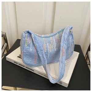 Detail of light blue hobo bag with rainbow wavy embroidery and textured F-pattern fabric