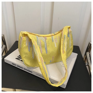 Close-up of bright yellow shoulder bag featuring colorful woven fringe texture and gold zipper