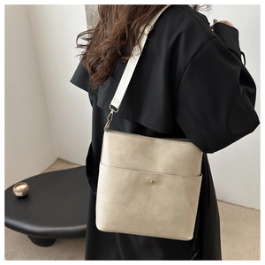Detail of beige tote bag with a front pocket and wide strap on a model's shoulder