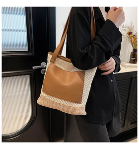 Detail of a woven straw tote bag with brown faux leather pockets and shoulder straps