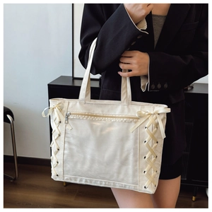 Detail of cream tote bag with ribbon weave side design and metal front zipper